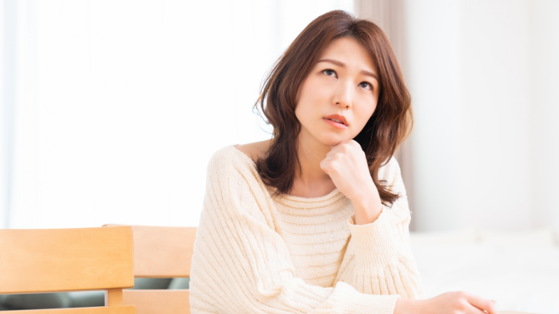 室内で頬杖をつきながら考え込む女性。40代で急に老けた気がすると感じる美容の悩みを表した写真